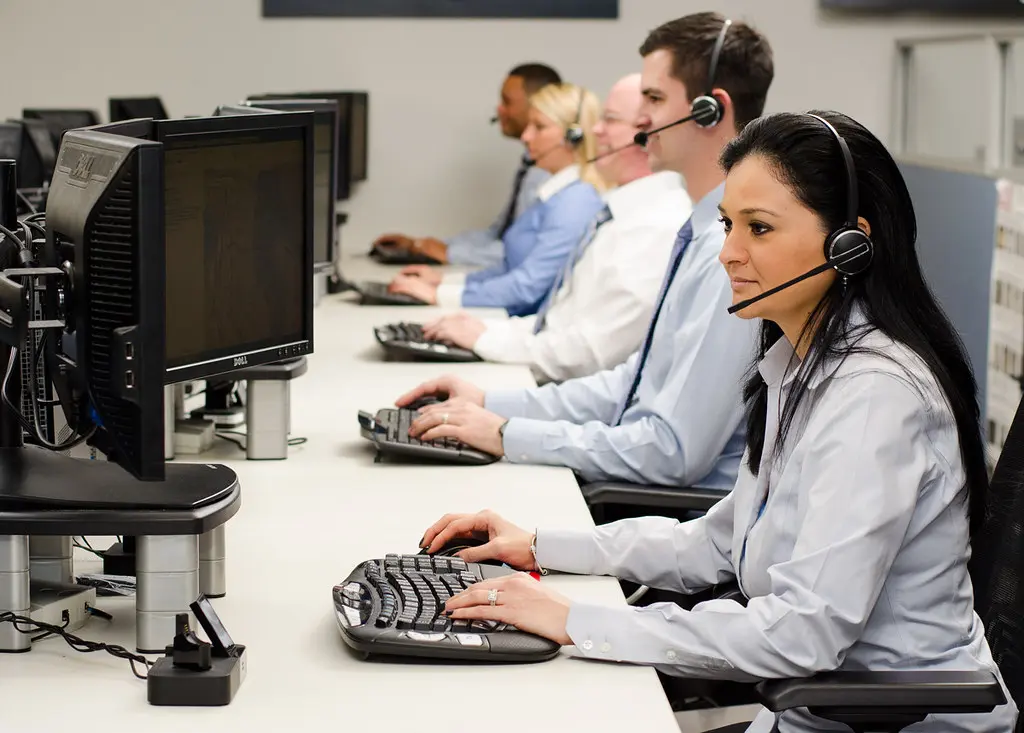 A row of support agents wearing headsets at their computers