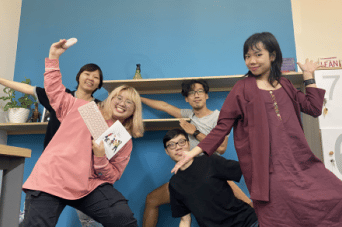 Colleagues posing playfully against a blue office wall