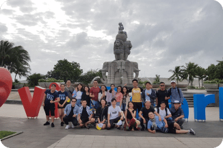 The team on an outdoor trip, posed in front of a monument