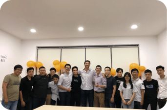 The BigIn team standing together in the office beneath gold balloons
