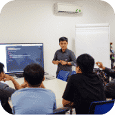 Two developers at a whiteboard, discussing a diagram on a screen