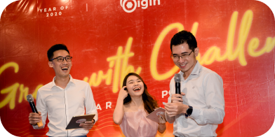 Three hosts with microphones on stage at a company event